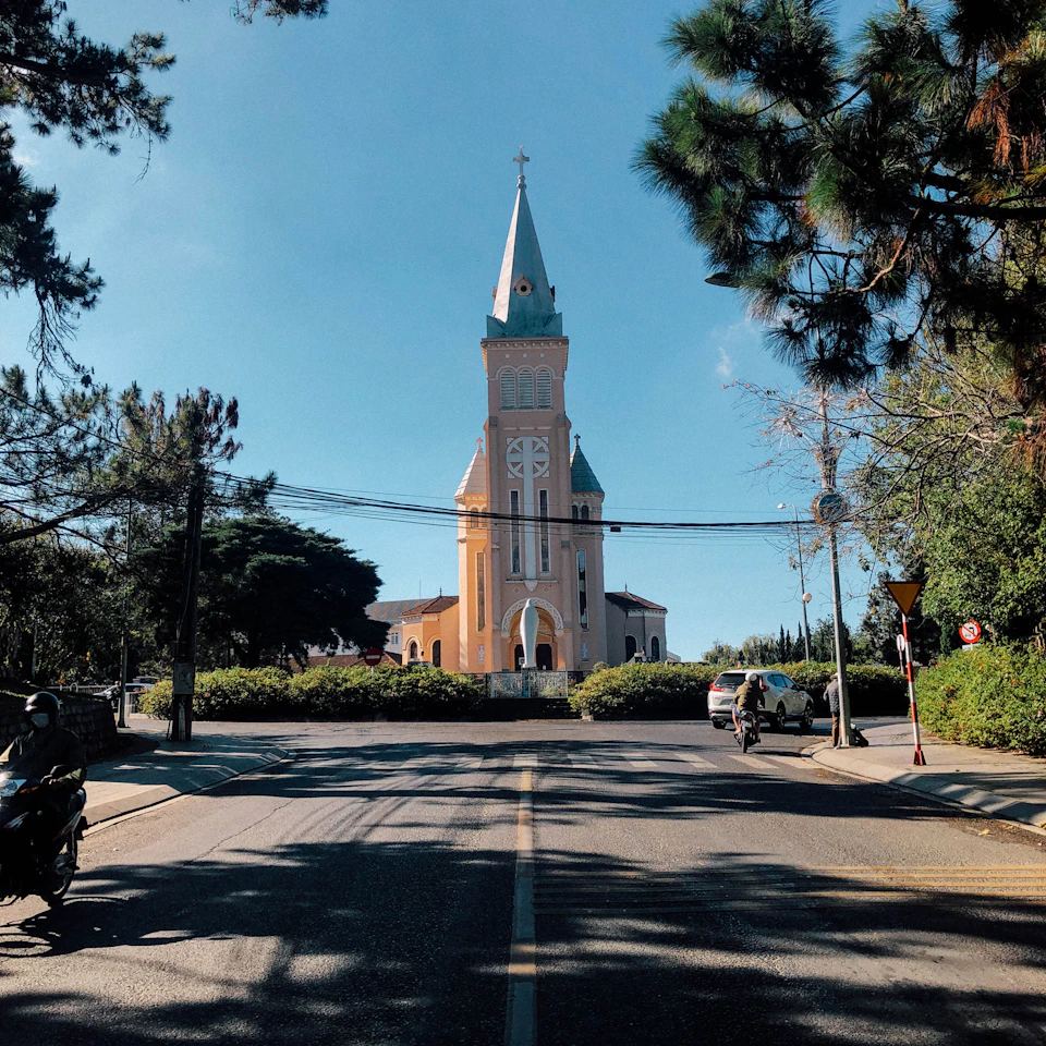 Da Lat pink cathedral under a clear blue sky on a bright sunny day with green pine trees