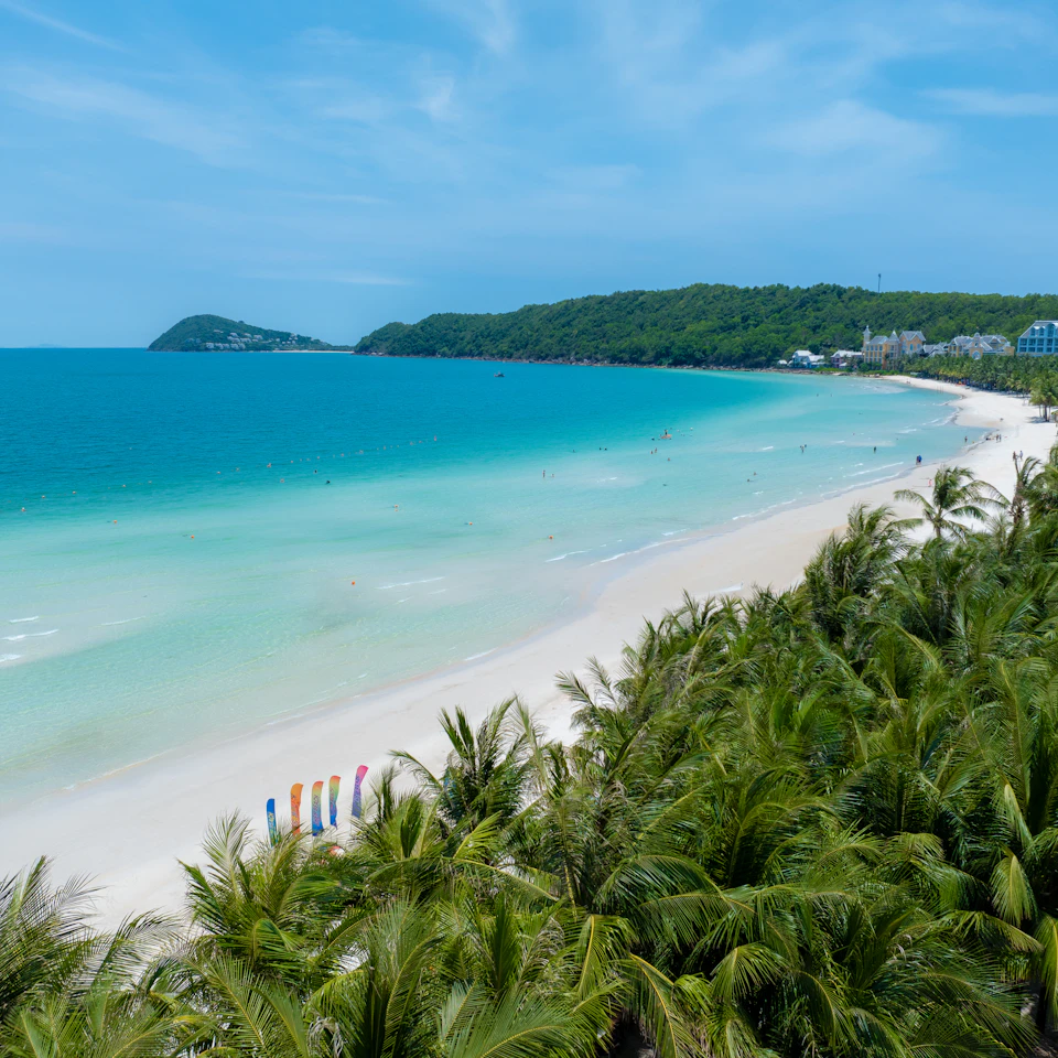 Bright turquoise sea and white sand beach lined with palm trees on Phu Quoc Island, Vietnam