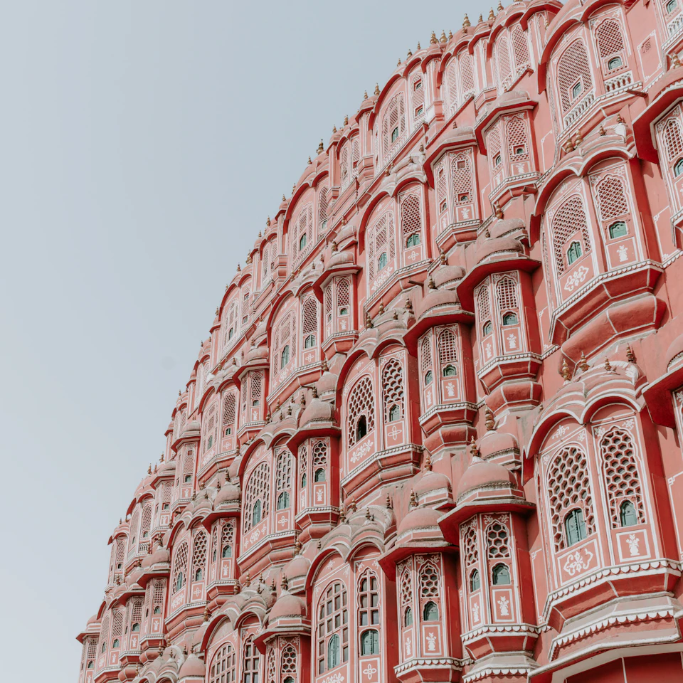 The pink Hawa Mahal palace in Jaipur, India glowing under bright daytime sun