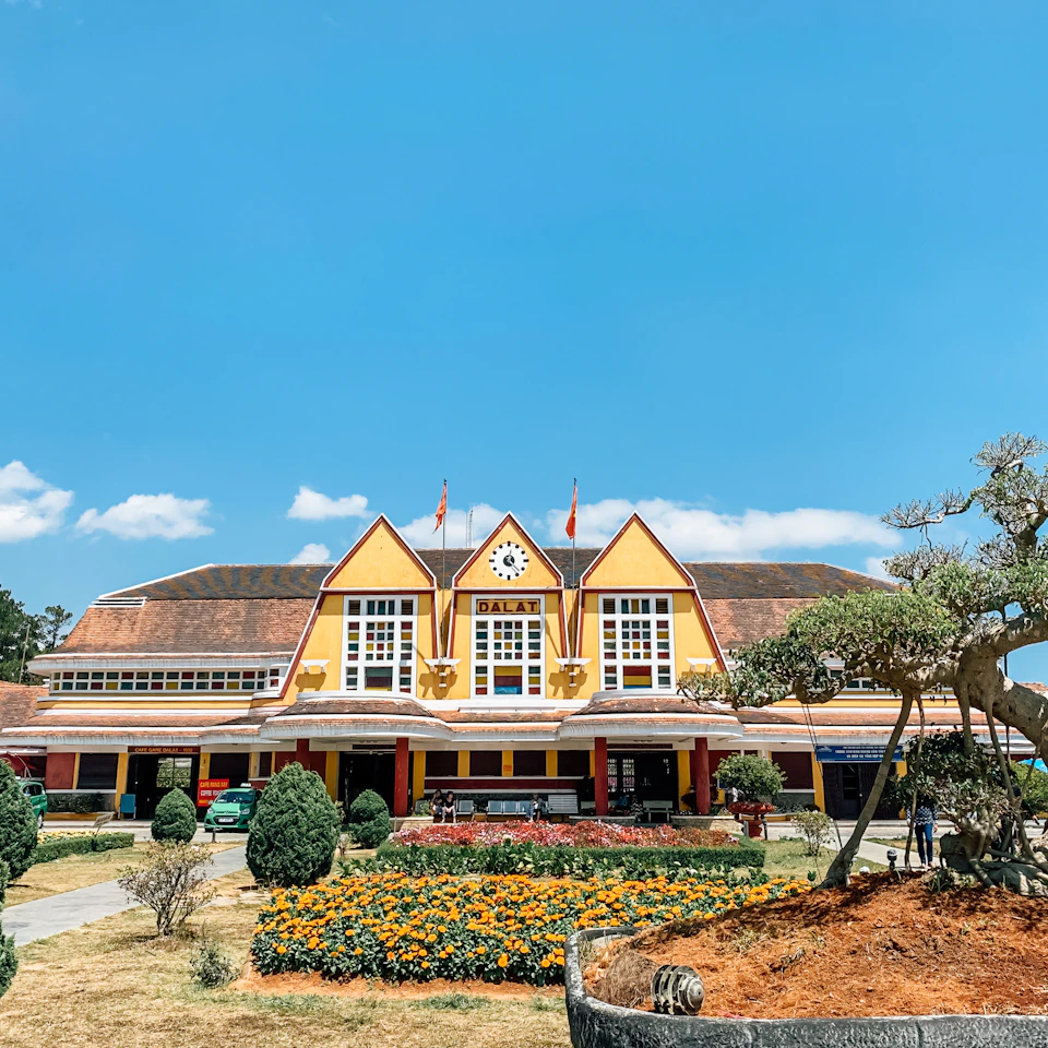 The yellow Da Lat railway station under a clear blue sky with bright marigold flowers