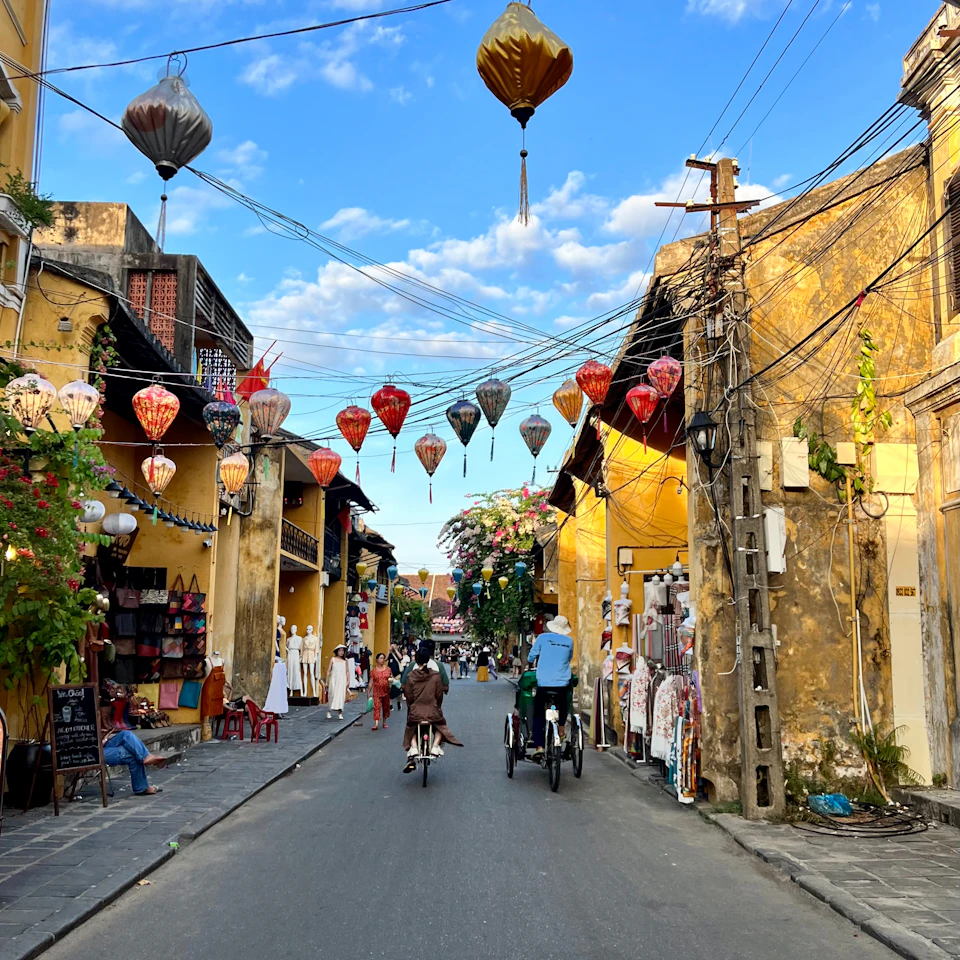 Sunny Hoi An old town street with yellow walls and colorful lanterns under a blue sky