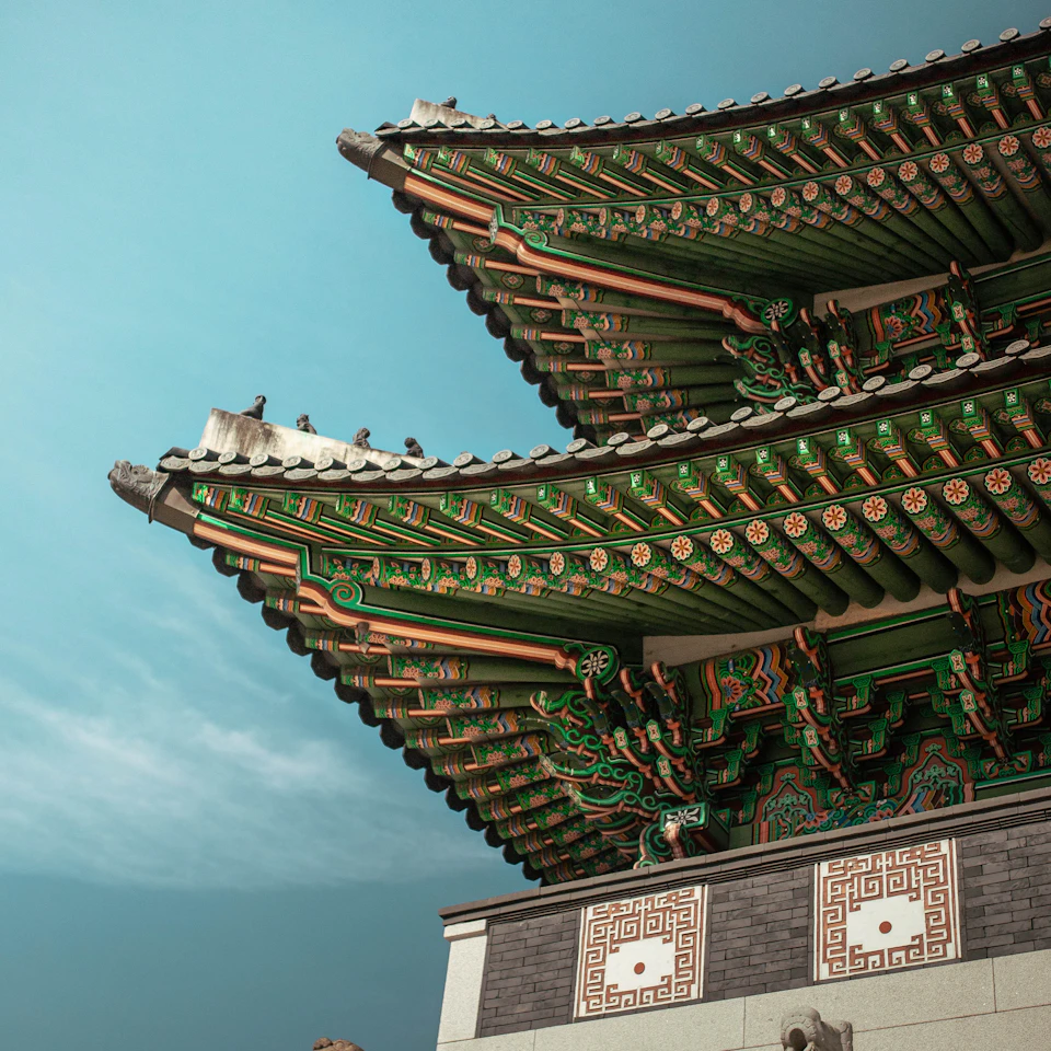 Gyeongbokgung palace roof eaves in green and red under a clear daytime sky in Seoul