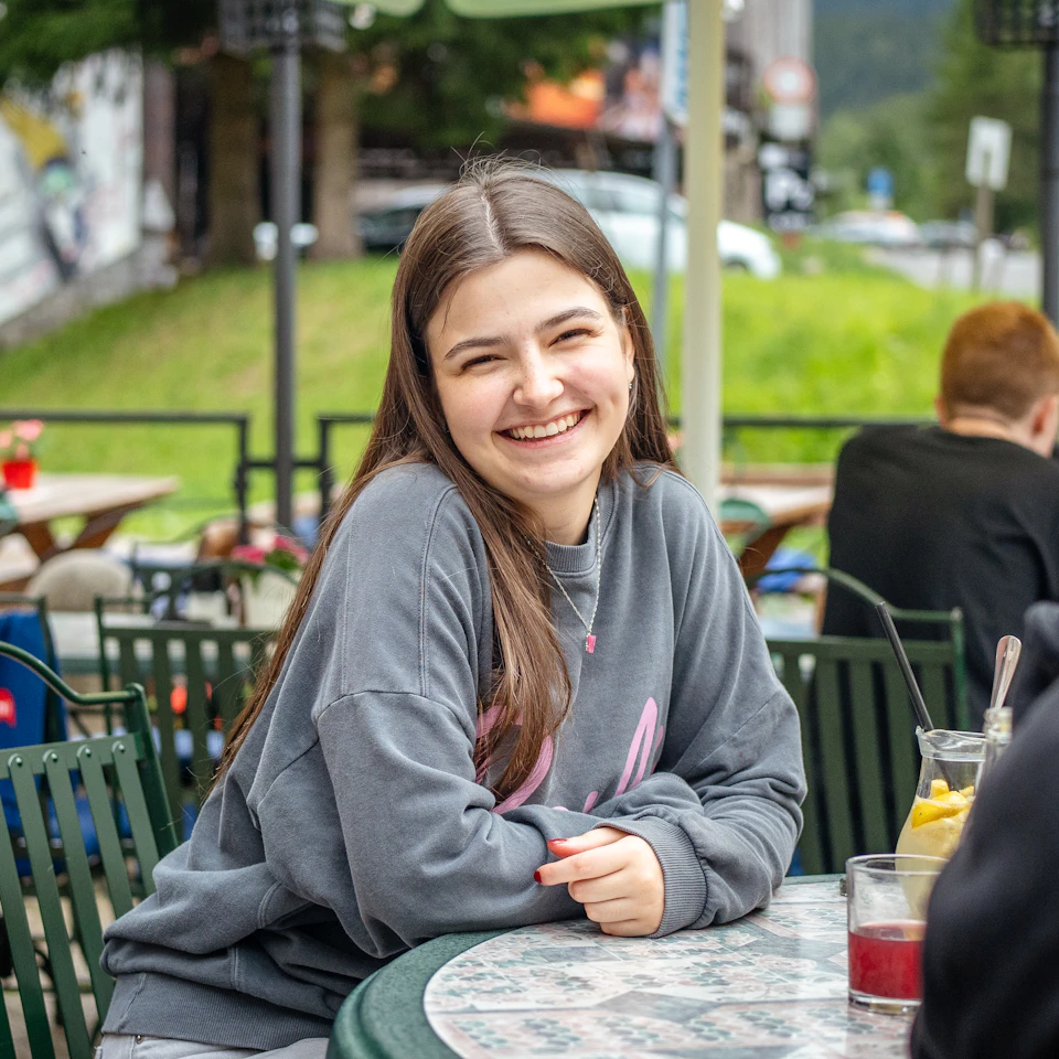 A young woman smiling and relaxing at a bright outdoor cafe on a fresh sunny day